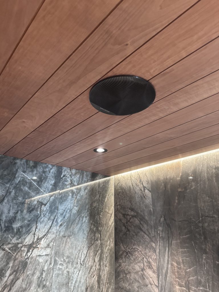 Kylpyhuoneen paneelikattoon asennettu Bang & Olufsen Celestial uppokaiutin. Kaiuttimen kattoasennus